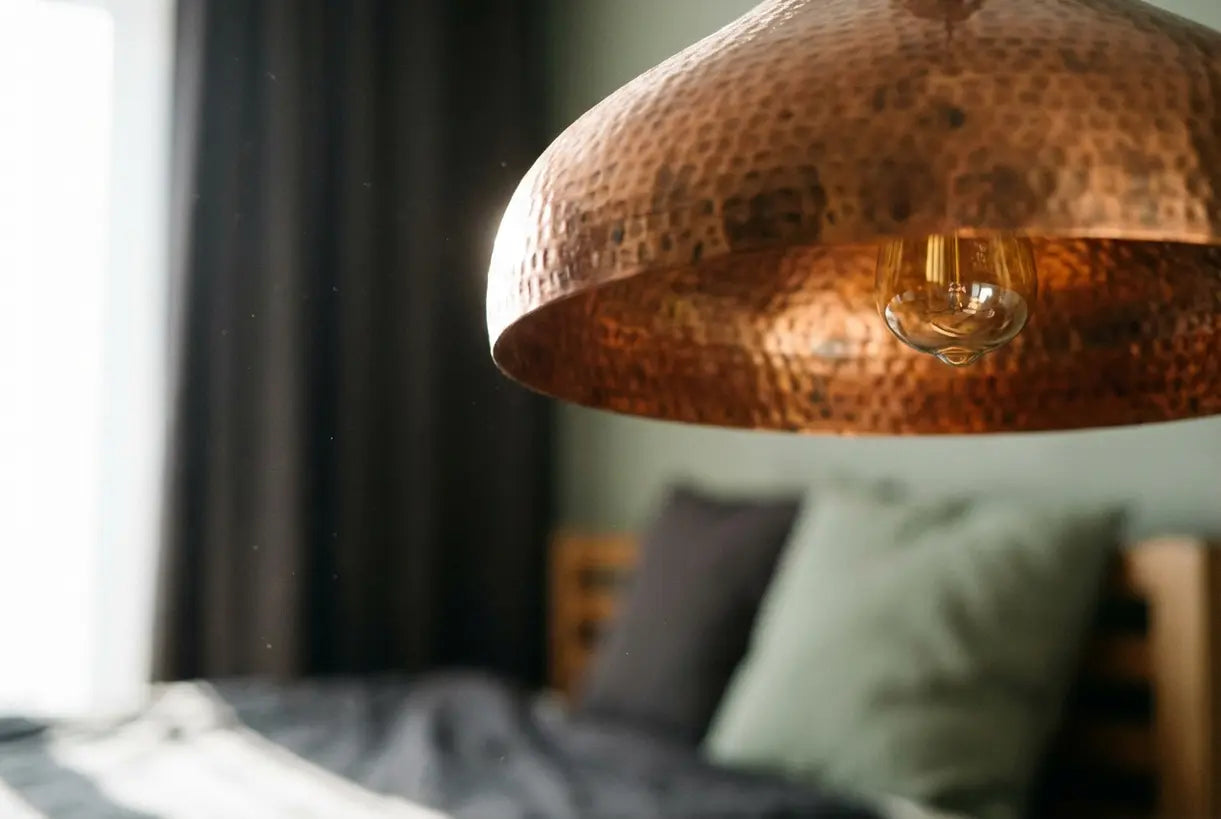 Close-up van de textuur van een gehamerde koperen hanglamp die een warme metaalafwerking toont