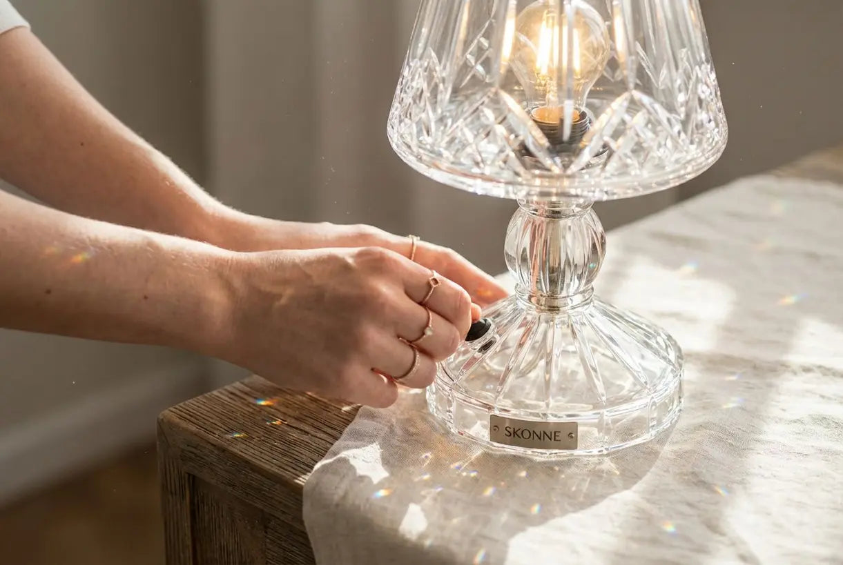 Handen passen een sprankelende kristallen tafellamp aan met prismatische lichtbrekingen