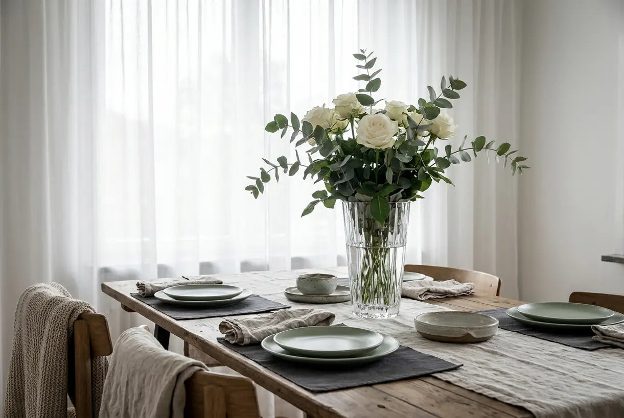 Elegante Kristallblumenvase mit weißen Rosen auf einem skandinavischen Esstisch