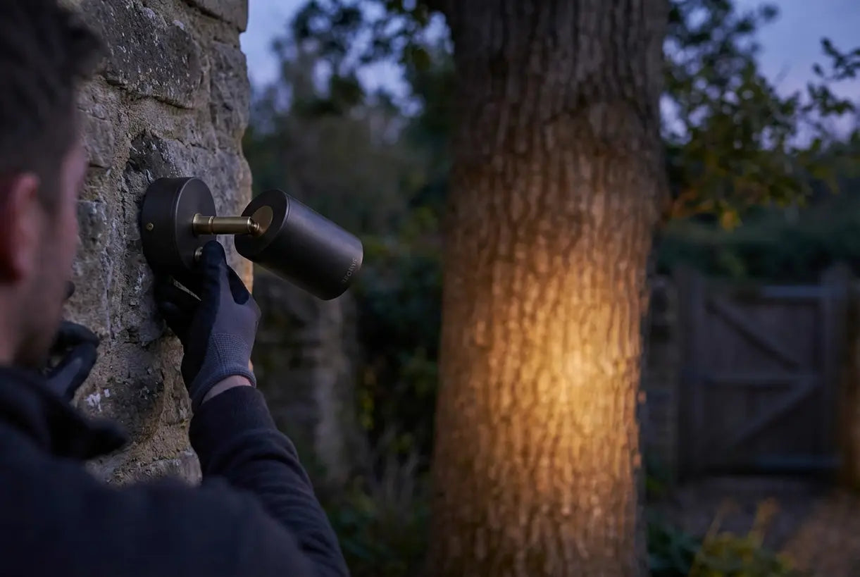 Handen stellen 's avonds een buitenspot bij die een boom aanlicht