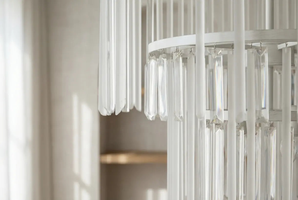 Close-up detail of a modern white chandelier with glass elements catching soft natural light