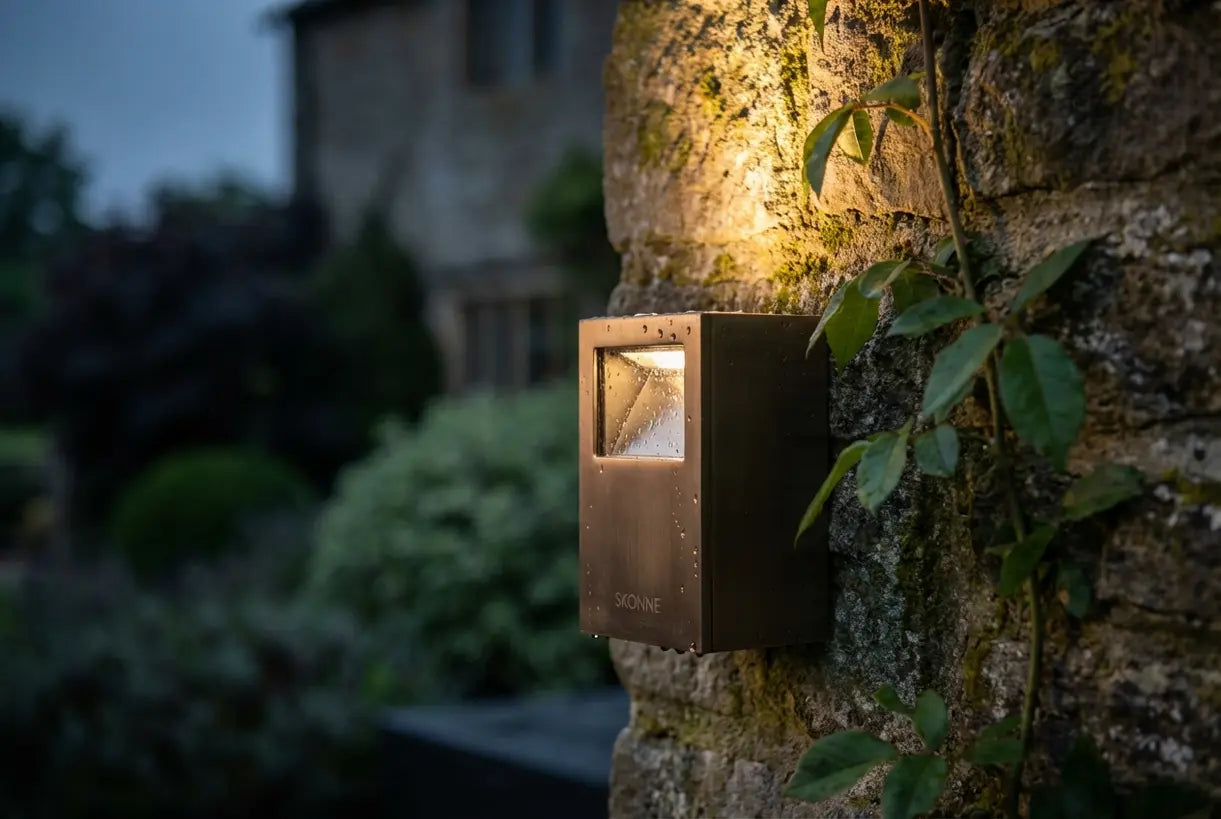 Close-up van moderne buitenwandlamp die een warme gloed werpt op een getextureerde stenen gevel