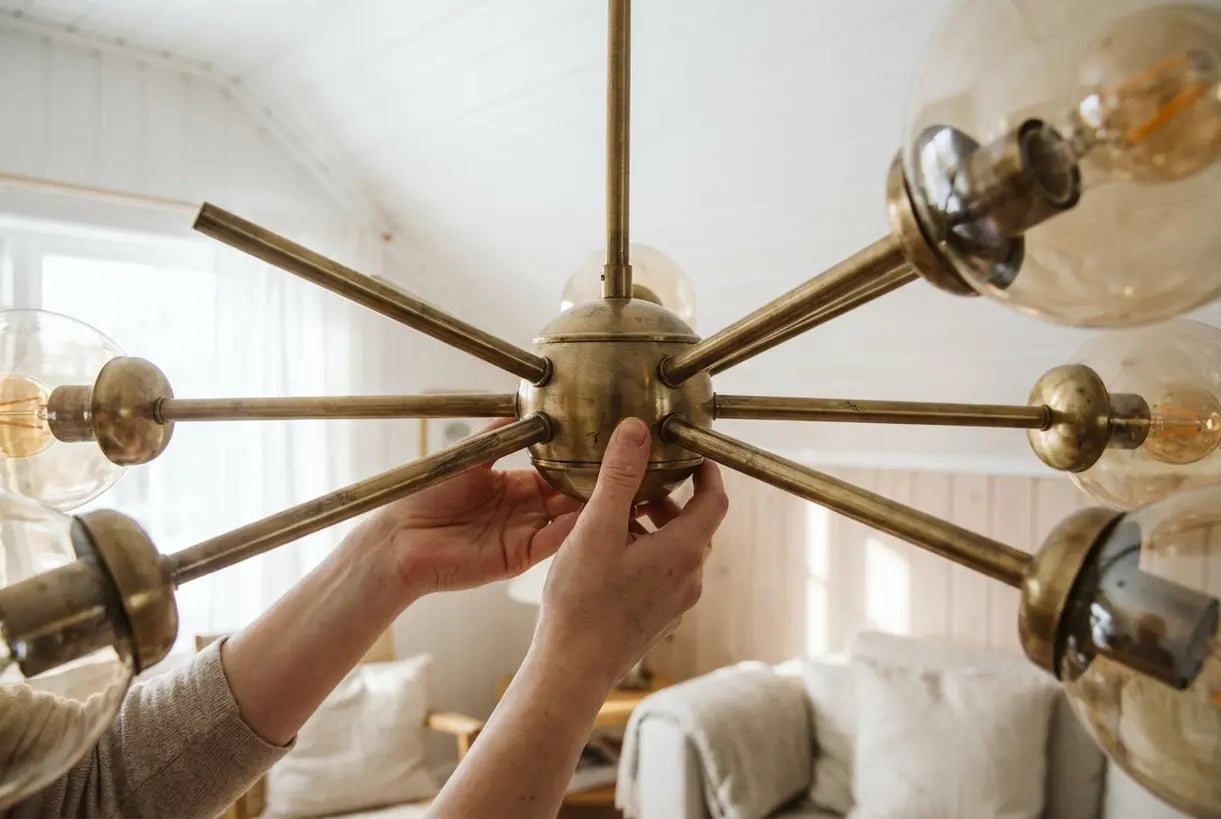 Handen die een messing mid-century plafondarmatuur met warme natuurlijke verlichting aanpassen