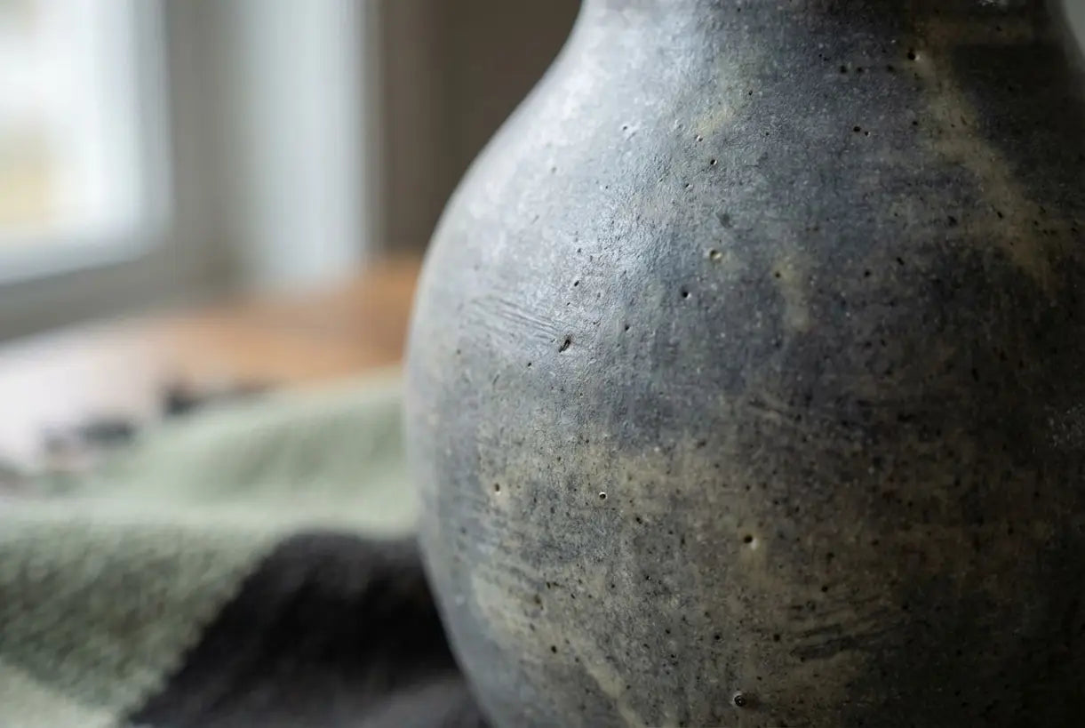 Detailopname van een handgemaakte grijze keramische vaas met glazuurtextuur voor een Scandinavisch interieur
