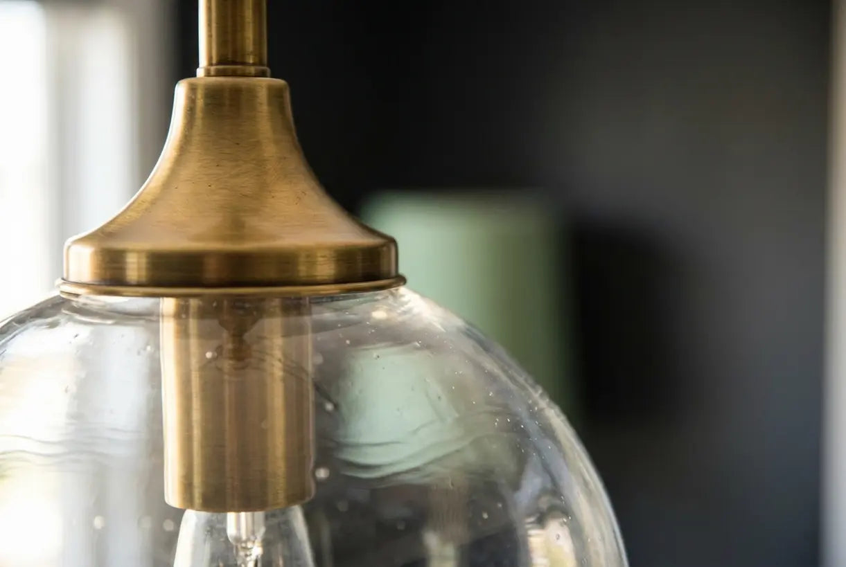 Goud- en glazen hanglamp close-up met messing hardware en heldere bol details