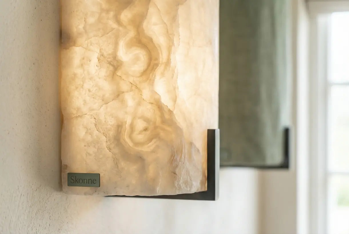 Close-up van een albasten wandlamp met natuurlijke steenaders en een warme, lichtgevende gloed