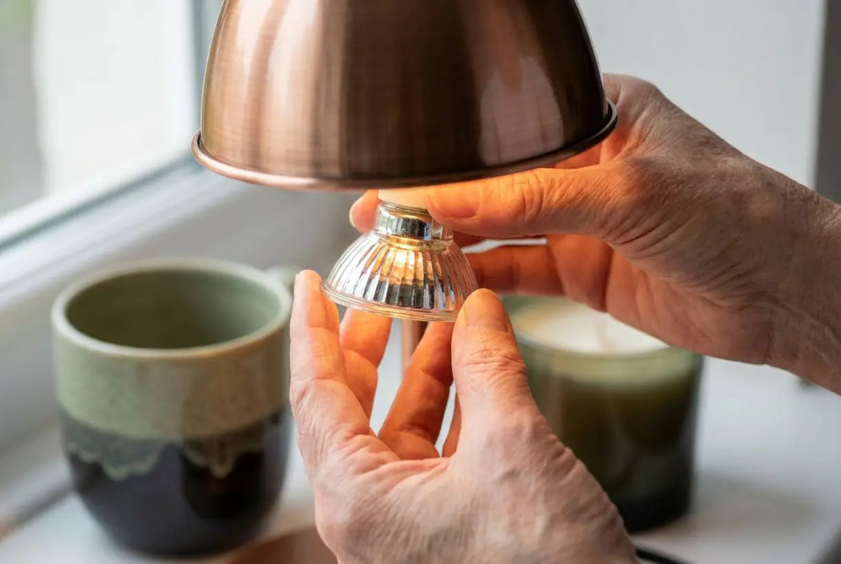 Handen installeren GU10 halogeenlamp in kaarsenwarmer armatuur
