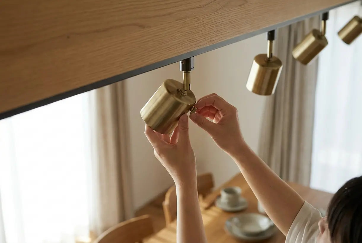 Hands adjusting modern track lighting in Scandinavian dining room