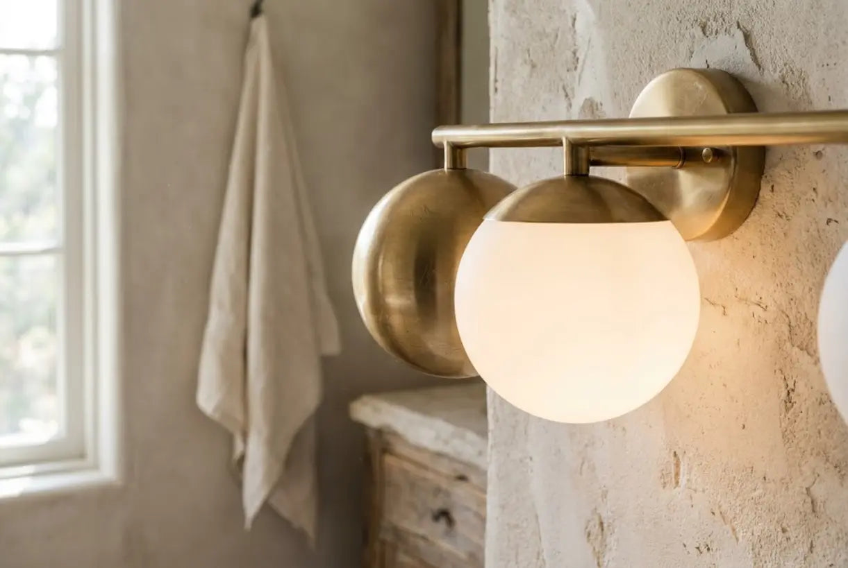 Close-up of brushed gold bathroom vanity light fixture with opal glass globe and warm metallic finish
