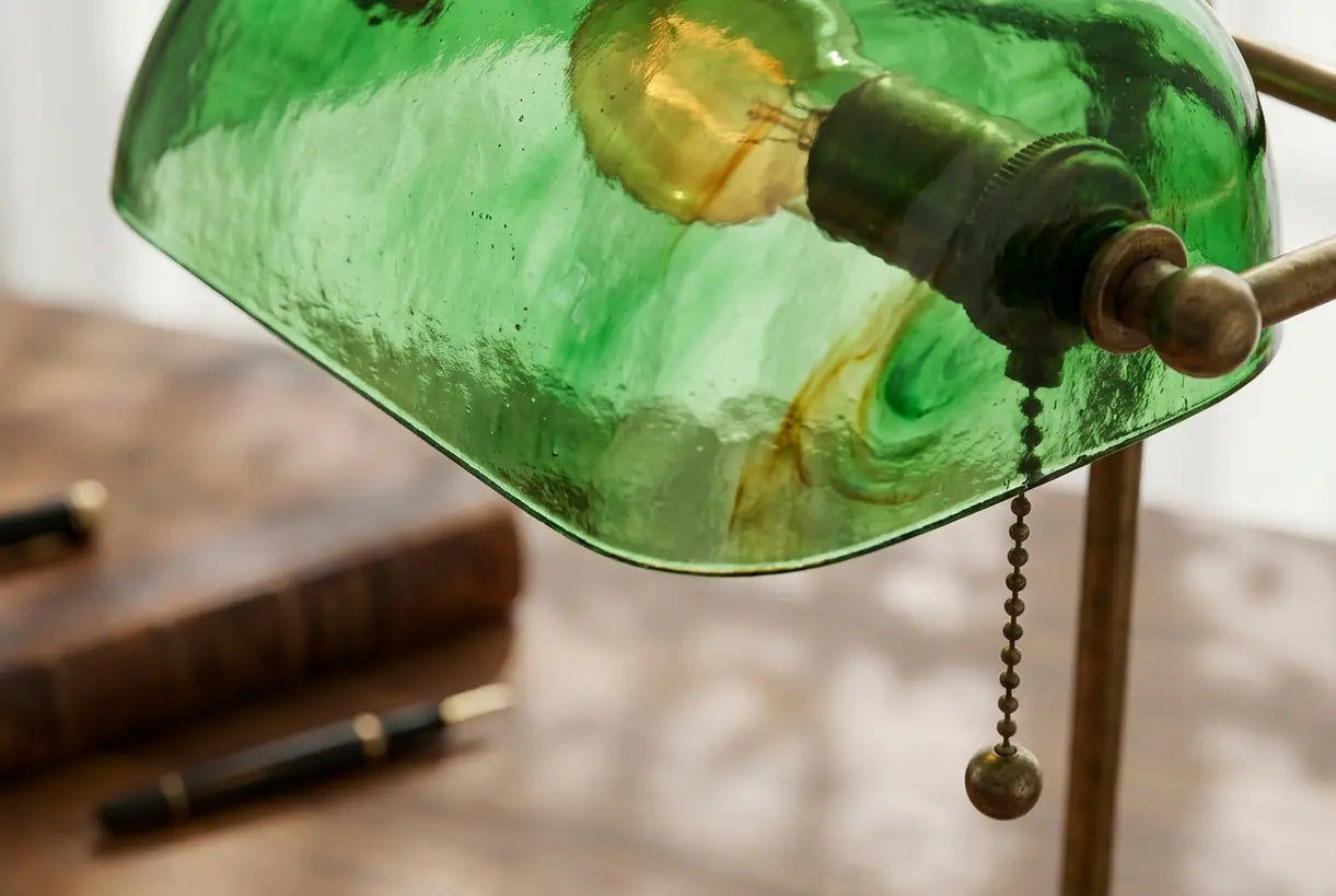 Close-up van vintage groene glazen kap op traditionele bankiers bureaulamp met messing beslag