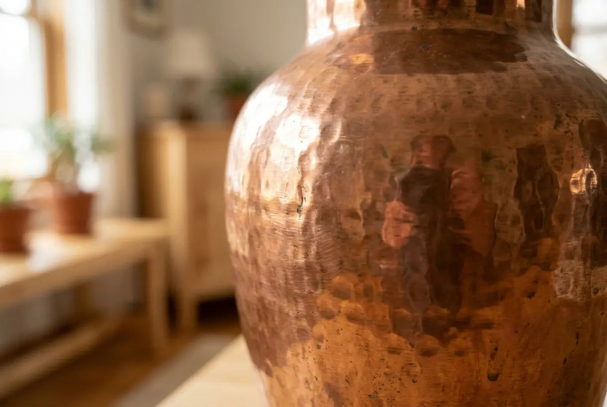 Detail einer gehämmerten Blumenvase aus Kupfer mit warmen, bernsteinfarbenen Reflexen