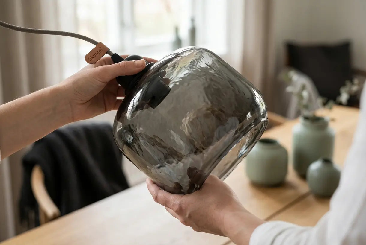 Handen stellen de rookglazen kap van een hanglamp bij in een hedendaags interieur