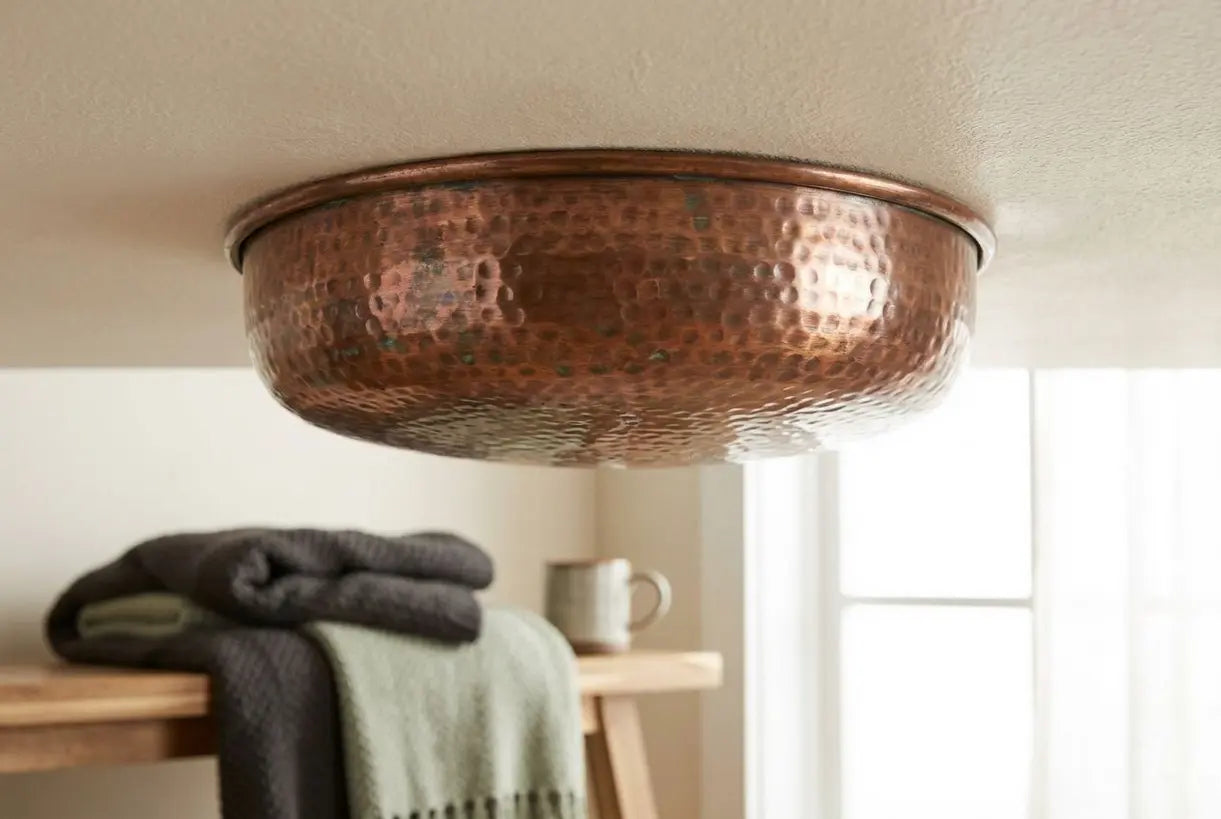Close-up van een koperen plafondlamp met warme metallic textuur en brons patina afwerking